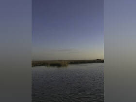 A serene view of a waterway with grasslands in the background, but the image lacks clarity and detail.