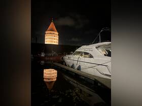 A serene night view of the 'Memel Lady' boat docked, reflecting the illuminated tower in the water — a picturesque scene capturing the charm of the harbor.