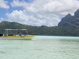 A vibrant speedboat anchored in crystal-clear waters, surrounded by lush green hills — an ideal setting for exploring tropical destinations.