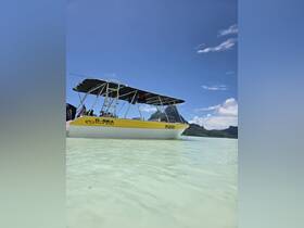 A vibrant yellow boat anchored in shallow turquoise waters, showcasing the stunning scenery of Bora Bora — perfect for exploring the beautiful lagoons.