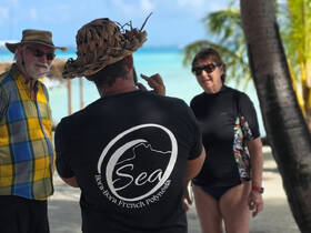 A group of travelers engages in conversation on a beautiful beach in Bora Bora, showcasing the vibrant atmosphere of this tropical paradise.