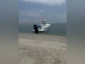A sleek speedboat is docked on a sandy shore, showcasing its fishing gear and ready for a day on the water.