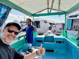 A cheerful selfie taken inside a boat, featuring the captain giving a thumbs up, showcasing the vibrant interior and relaxed atmosphere of the vessel.