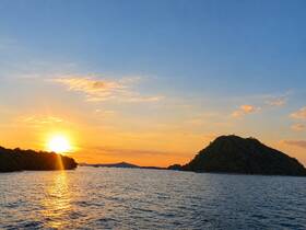 A breathtaking sunset over a tranquil coastline, with lush islands silhouetted against the vibrant sky — a perfect scene for evening boat cruises.