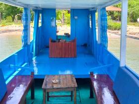 Interior view of a colorful boat cabin featuring seating and a helm area, perfect for relaxing during a day on the water.
