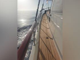 A serene view of the side deck of a yacht, showcasing polished wood and calm waters, perfect for a peaceful sailing experience.