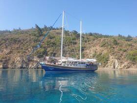 A stunning side view of the yacht 'Xanthos' docked in tranquil waters, surrounded by lush greenery — perfect for serene sailing adventures.