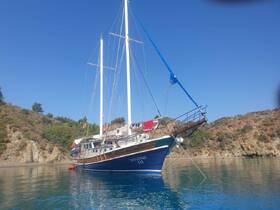 A beautiful sailboat anchored in calm waters, showcasing its elegant hull and rigging against a scenic backdrop of hills.