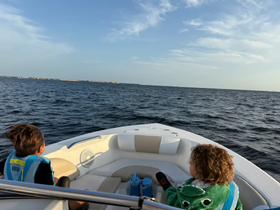 Two children enjoy a scenic boat ride on the ocean, showcasing the joy of family adventures on the water.