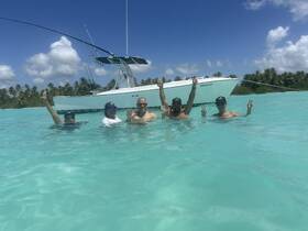 A cheerful group enjoys a refreshing swim in crystal-clear waters, with their boat anchored nearby — a perfect day of fun and relaxation on the water.