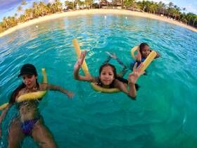 A joyful moment captured as a family enjoys swimming in crystal-clear waters, perfect for a fun day at the beach.