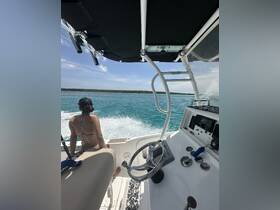 A view from the helm of a boat with a passenger enjoying the ride, showcasing the interior layout and steering controls against a backdrop of vibrant blue waters.