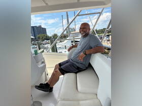 A man relaxes in the comfortable seating area of a boat's interior, showcasing a stylish helm and inviting atmosphere for a day on the water.