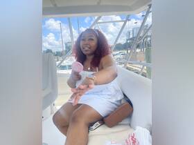 A woman relaxes inside a boat, enjoying the ambiance with a handheld fan. The interior setting showcases comfortable seating, perfect for a day on the water.