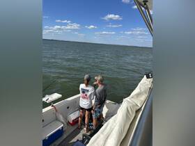 A couple enjoys a fishing trip on a boat, casting their lines into the water under a clear blue sky — perfect for outdoor adventures and bonding time.