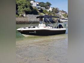 A sleek speedboat named 'Black Marlin' docked in shallow waters, showcasing its stylish design against a scenic backdrop of lush greenery and coastal homes.