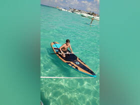 A child paddleboards in the crystal-clear turquoise waters, showcasing a fun water activity perfect for family adventures.