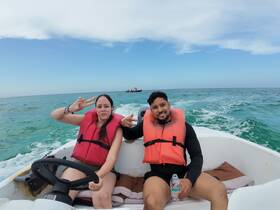 A couple enjoys a fun day on the water, sporting life jackets and smiles while cruising in their boat — perfect for adventure seekers.