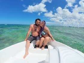 A couple enjoys a romantic moment on a boat in the clear ocean waters, perfect for a sunny day adventure.