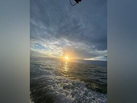 A stunning sunset over the ocean, with gentle waves reflecting the golden light — a perfect moment for a serene boating experience.