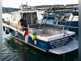 A fishing tourism boat docked in a serene harbor, showcasing its spacious deck and vibrant fenders — perfect for exploring the waters and enjoying fishing adventures.