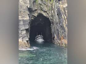 A boat navigates through a stunning cave entrance, showcasing the beauty of marine exploration and the allure of hidden natural wonders.