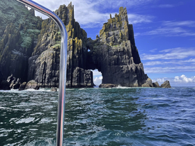 A stunning view of a dramatic rock formation emerging from the ocean, showcasing the natural beauty of the coastline — perfect for sightseeing and adventure tours.