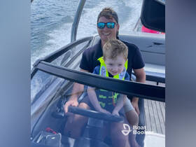 A joyful moment captured as a father and son navigate a boat together, showcasing family fun on the water with smiles and safety gear.