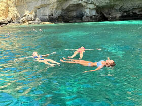 A group of friends enjoys a relaxing day floating in the crystal-clear waters, surrounded by stunning natural scenery — perfect for summer adventures.