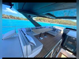 A stylish interior view of a yacht's lounge area featuring comfortable seating and a dining table, perfect for relaxing while enjoying the stunning turquoise waters outside.