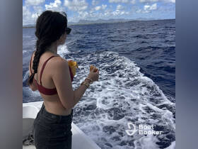 A woman enjoys a scenic view of the ocean while holding a snack and drink aboard a boat, capturing the essence of a relaxing day on the water.