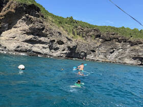 A lively scene of a group enjoying a day of swimming and kayaking in clear blue waters, surrounded by stunning rocky cliffs — perfect for adventure seekers.