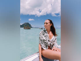 A woman enjoys the stunning tropical scenery while on a boat, with a picturesque island backdrop and clear turquoise waters — perfect for a day of adventure and relaxation.