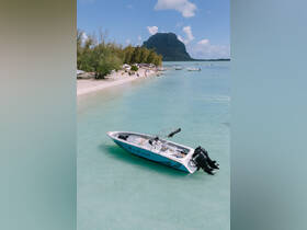 A stunning aerial view of the 'Sun Chaser 2' speedboat docked in crystal-clear waters, surrounded by a picturesque beach and lush greenery, perfect for a day of adventure on the water.