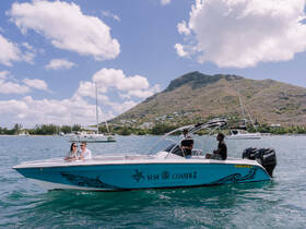 A couple enjoys a scenic boat ride on the 'Sun Chaser 2', surrounded by stunning ocean views and lush mountains — perfect for romantic adventures.