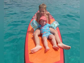 A joyful moment captured with two children enjoying paddleboarding in clear turquoise waters, perfect for family adventures and summer fun.