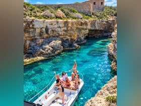 A lively group of friends enjoys a sunny day on a boat in a stunning turquoise cove, perfect for summer adventures and celebrations.