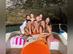 A joyful group of friends poses together on a boat inside a stunning cave, capturing a memorable moment during their adventure.