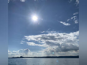 A scenic view of the sky and water, capturing the beauty of nature with clouds and sunlight, but lacks clarity and identifiable subjects.