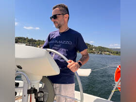 A man navigates the helm of a sailboat, enjoying a sunny day on the water — perfect for sailing enthusiasts and adventure seekers.