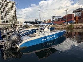 A sleek speedboat named 'Rey Salomón II' docked at a marina, showcasing its modern design against a backdrop of urban architecture.