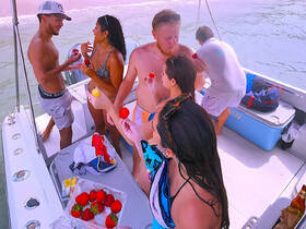 A lively group enjoys a fun moment on a boat, sharing strawberries and drinks, perfect for a summer party on the water.