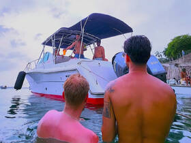 A group of friends enjoys a lively moment in the water, interacting with a boat in the background — perfect for summer fun and celebrations on the water.