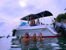 A lively group of friends enjoys a fun day in the water with drinks, celebrating aboard a boat — perfect for summer parties and memorable outings.