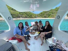 A lively group of friends enjoys a boat party, celebrating with cocktails and snacks while surrounded by stunning turquoise waters — perfect for a fun day on the water.