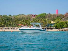 A lively group enjoys a day on the water aboard a boat, cruising near a beautiful beach surrounded by palm trees — perfect for sun-soaked adventures.