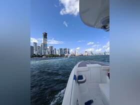 A scenic view from a boat cruising through the waters of Miami, showcasing the vibrant city skyline and iconic attractions in the background.