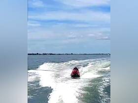 A thrilling moment captured as a person enjoys tubing behind a boat, showcasing the excitement of water sports on a sunny day.