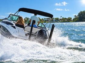 A couple enjoys a thrilling ride on a speedboat, creating splashes as they navigate through the sparkling waters — perfect for adventure seekers.