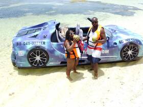 A fun beach moment with a couple enjoying fresh coconuts next to a unique jet car — perfect for adventurous outings and memorable experiences on the water.